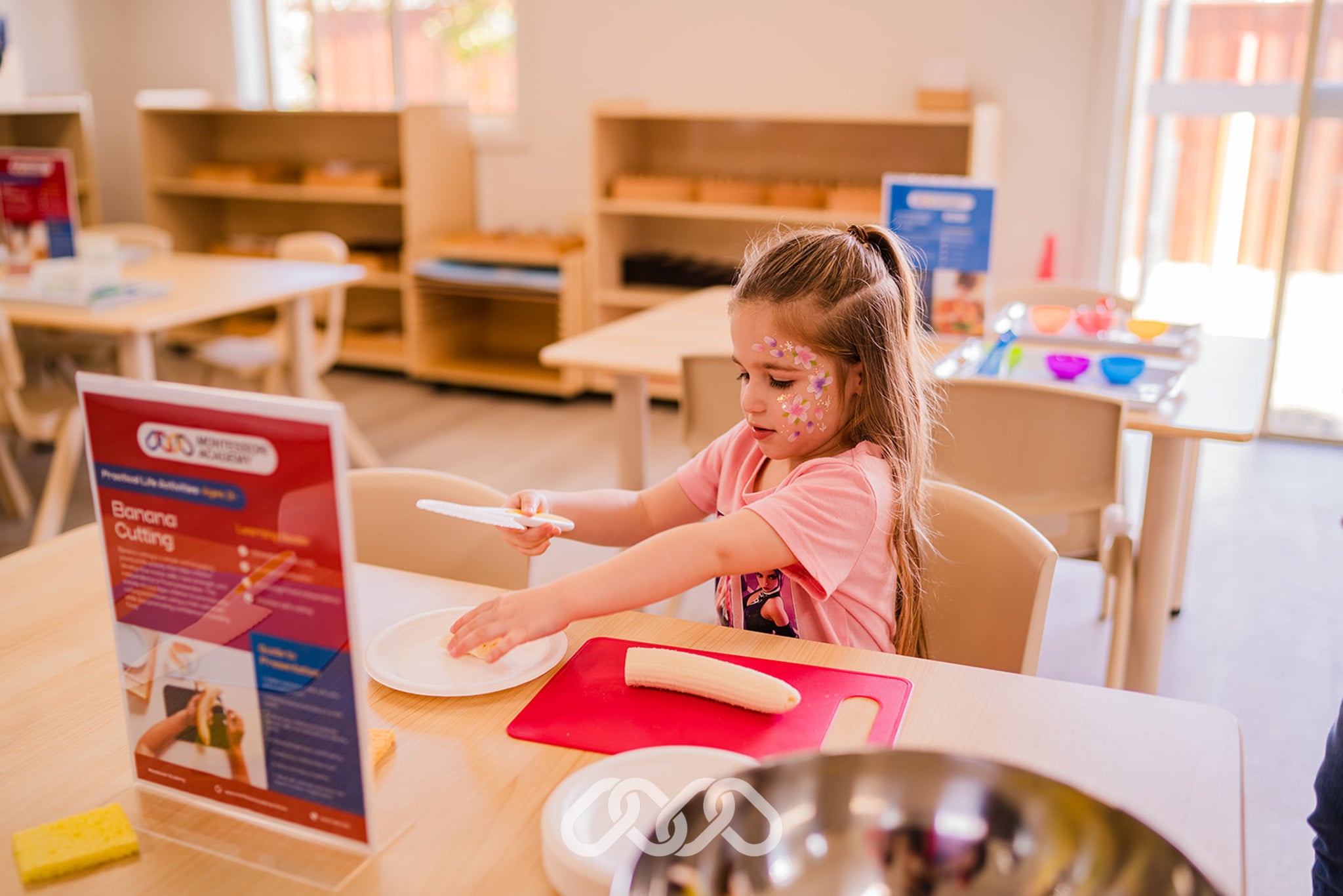 Child completing a Montessori banana cutting activity at Narellan Vale Montessori Academy, developing hand-eye coordination and fine motor skills.