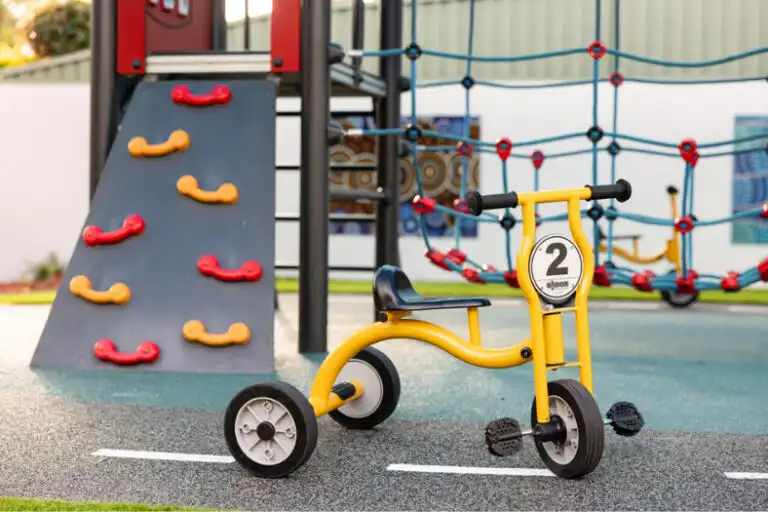 Children’s tricycle and playground equipment at Mount Annan Montessori childcare with climbing wall and rope net structure