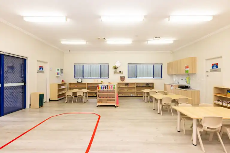 Montessori classroom at Mount Annan childcare with wooden tables, kitchen area and open learning space