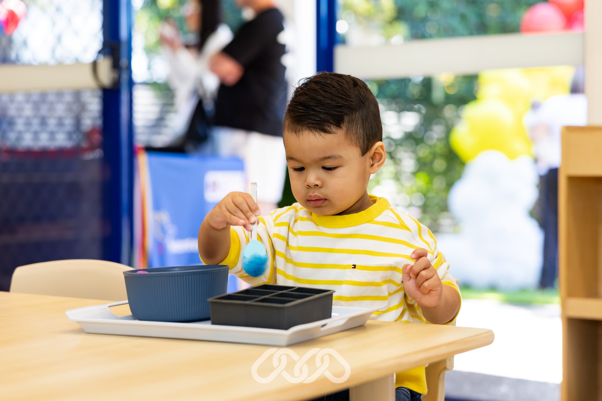 Child completing a Montessori tong transfer activity at Mount Annan Montessori Academy, developing pincer grip strength, hand-eye coordination and fine motor skills.