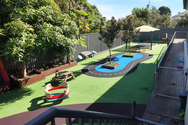 Shaded outdoor play area at North Parramatta Montessori Academy with ride-on equipment and open play space