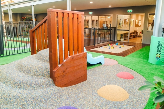 Outdoor play area at Revesby Montessori Academy with sandpit, slide and soft-fall surface
