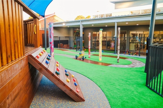Outdoor climbing area at Revesby Montessori Academy with wooden play structure and soft-fall space