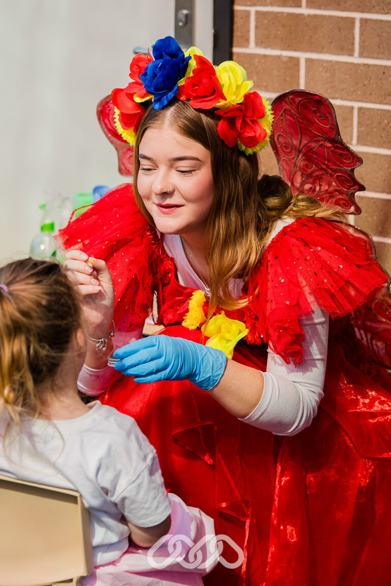 Face painter creating a colourful design at the Northmead Montessori Academy Grand Opening.