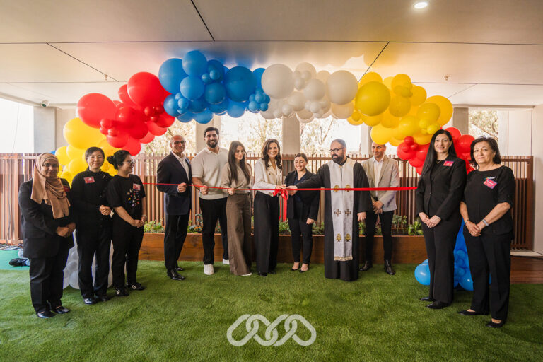 Montessori academy leadership, local community leaders and the team gather under colourful balloon arch for the ribbon cutting of Bankstown North Montessori Academy grand opening