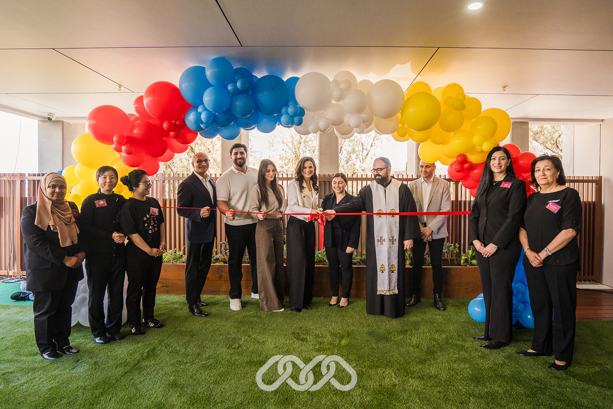 Montessori academy leadership, local community leaders and the team gather under colourful balloon arch for the ribbon cutting of Bankstown North Montessori Academy grand opening